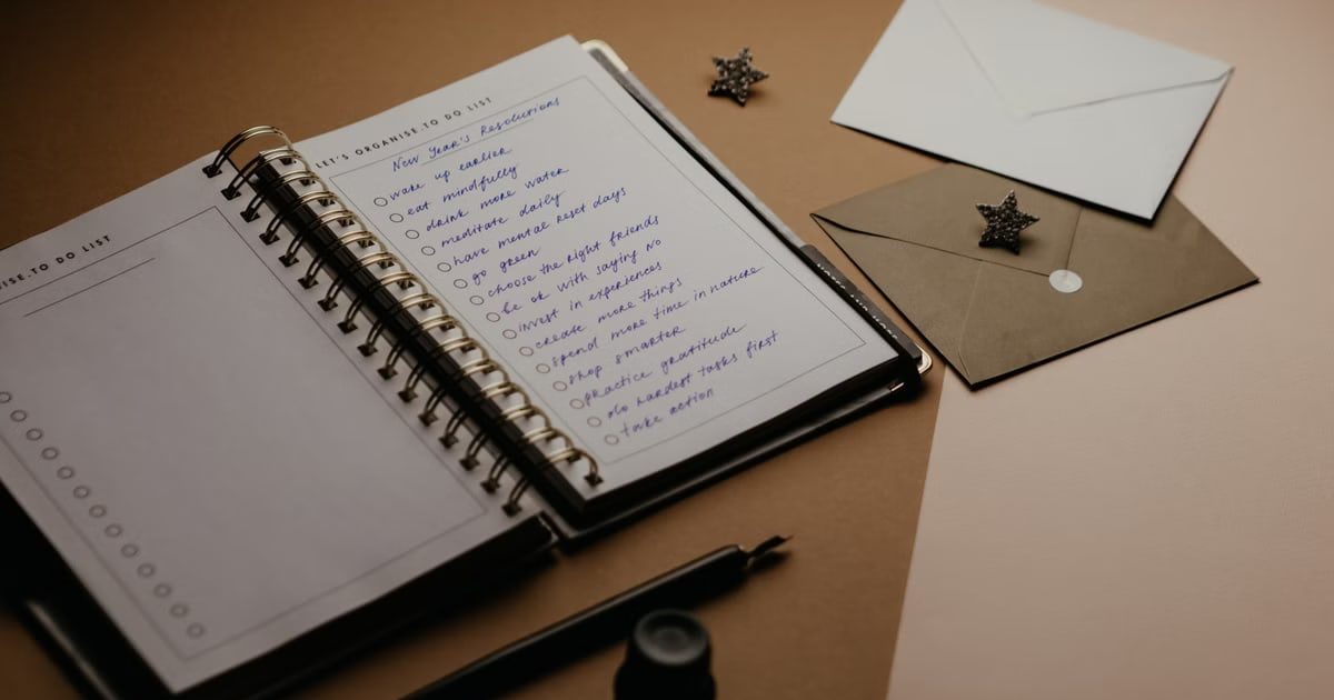 A tidy desk setup featuring a planner, to-do list, envelopes, and a pen.