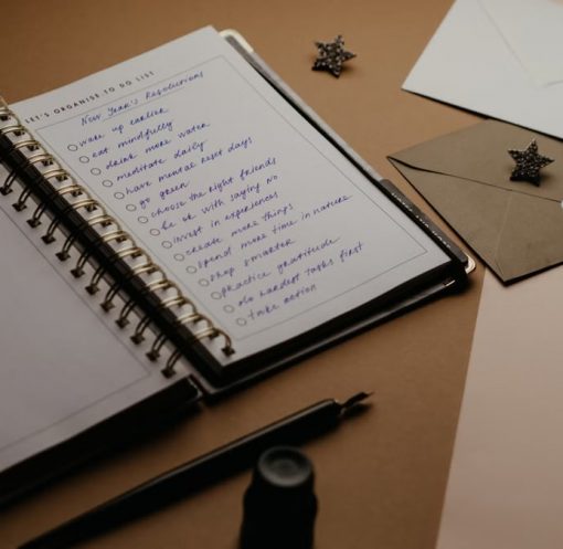 A tidy desk setup featuring a planner, to-do list, envelopes, and a pen.