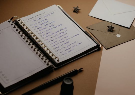 A tidy desk setup featuring a planner, to-do list, envelopes, and a pen.