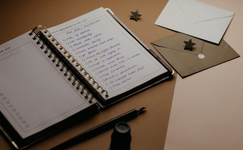 A tidy desk setup featuring a planner, to-do list, envelopes, and a pen.